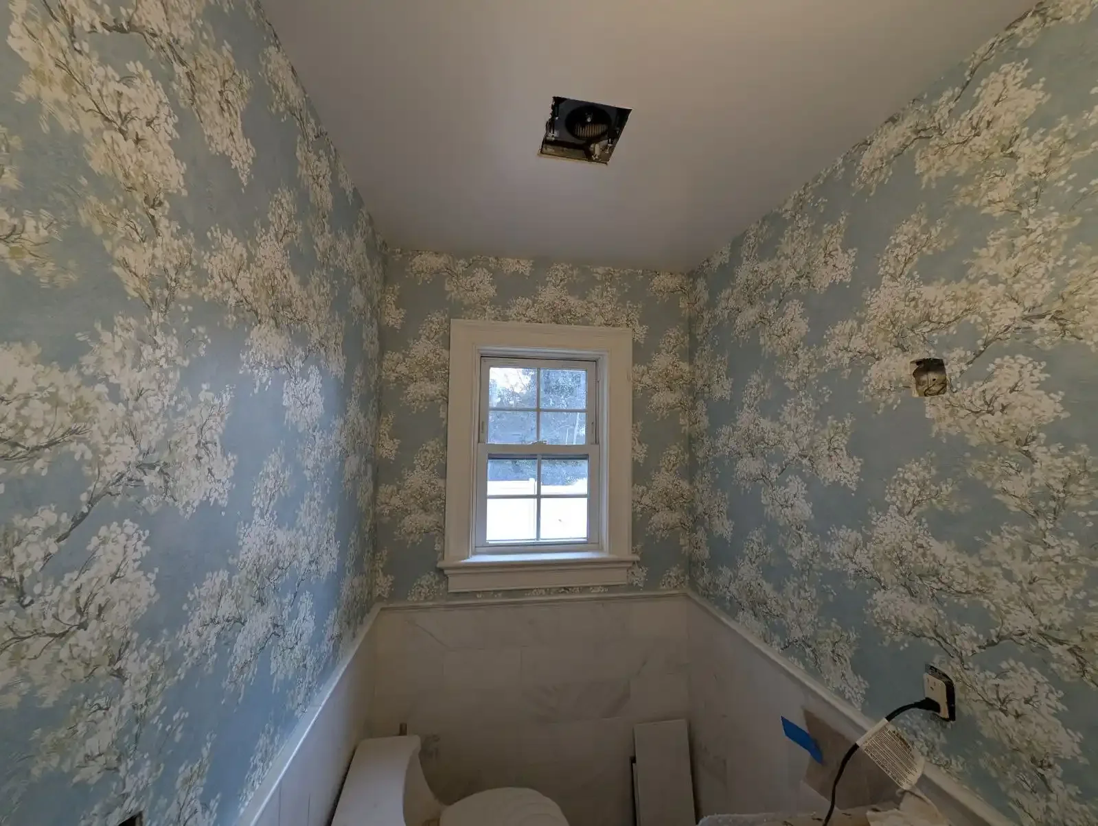 A blue wallpapered room with patterned walls and a window