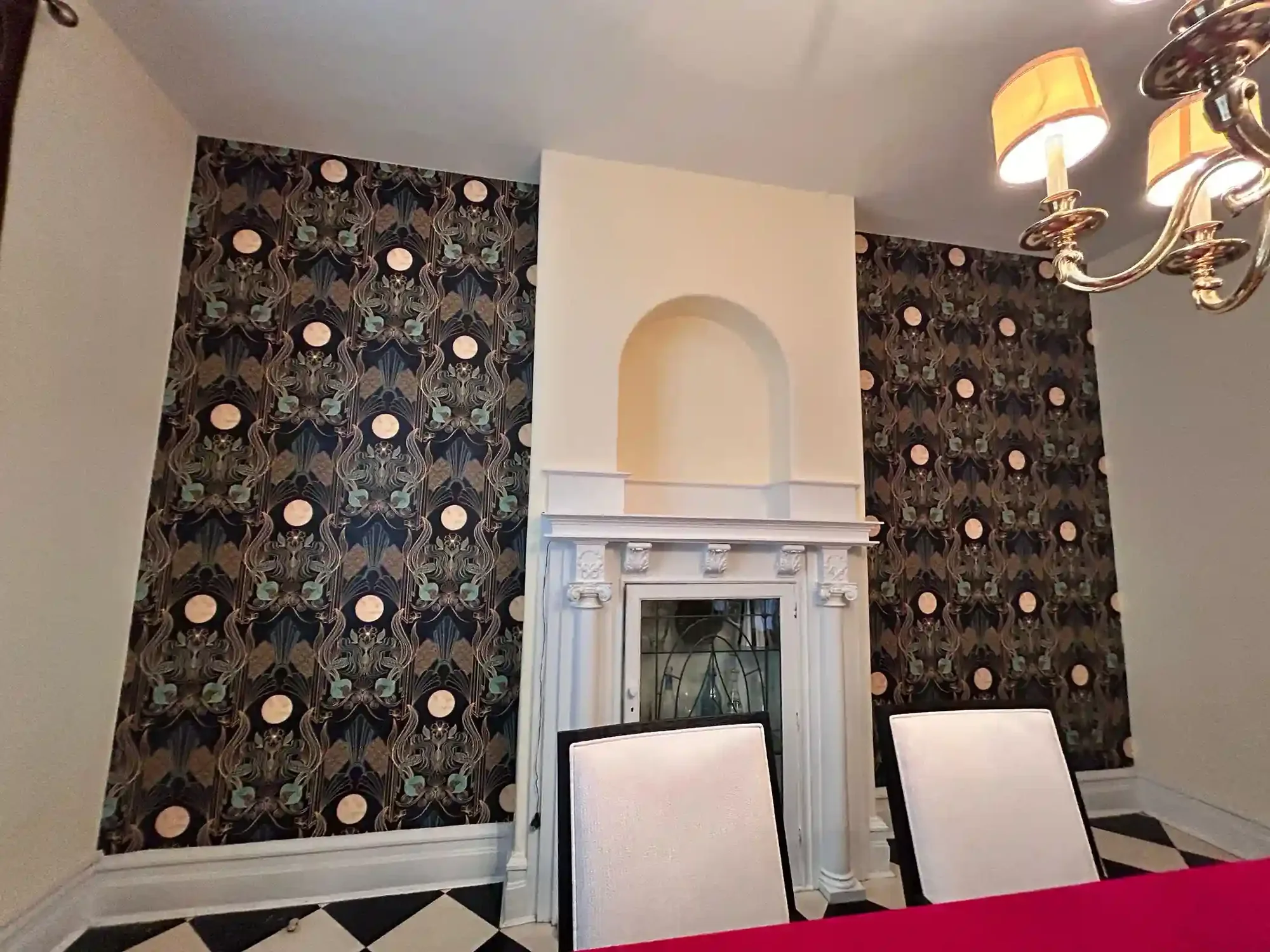 Dark patterned wallpaper framing a pale fireplace and interior furnishings