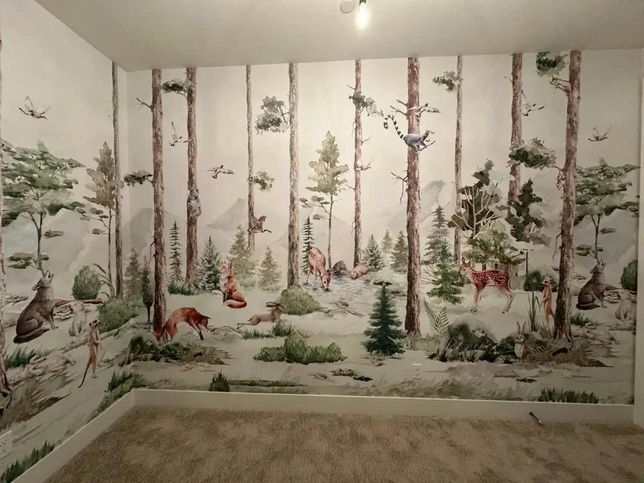 A woodland scene printed as a panoramic wallpaper mural above a calm bedroom interior